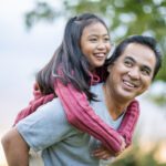 Father Giving His Daughter A Piggyback Ride Stock Photo