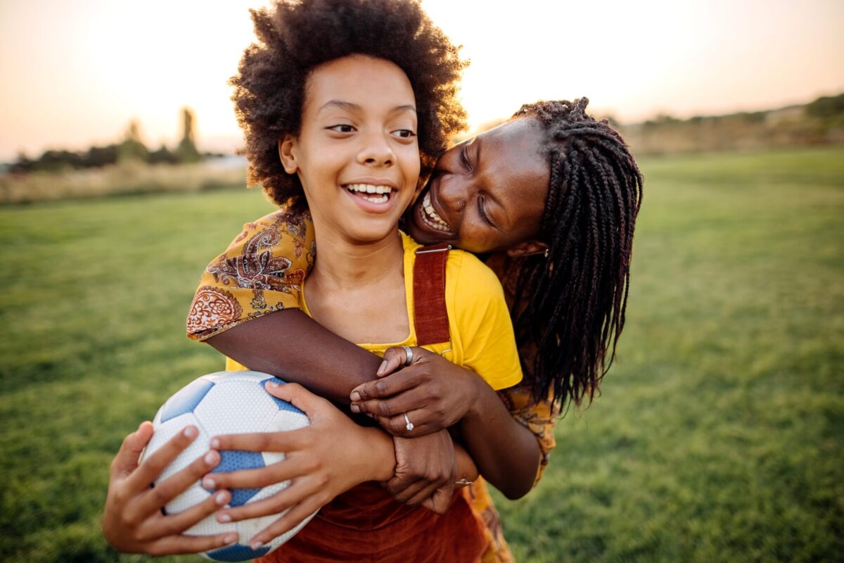 an adult and child playing soccer outside for a healthier summer