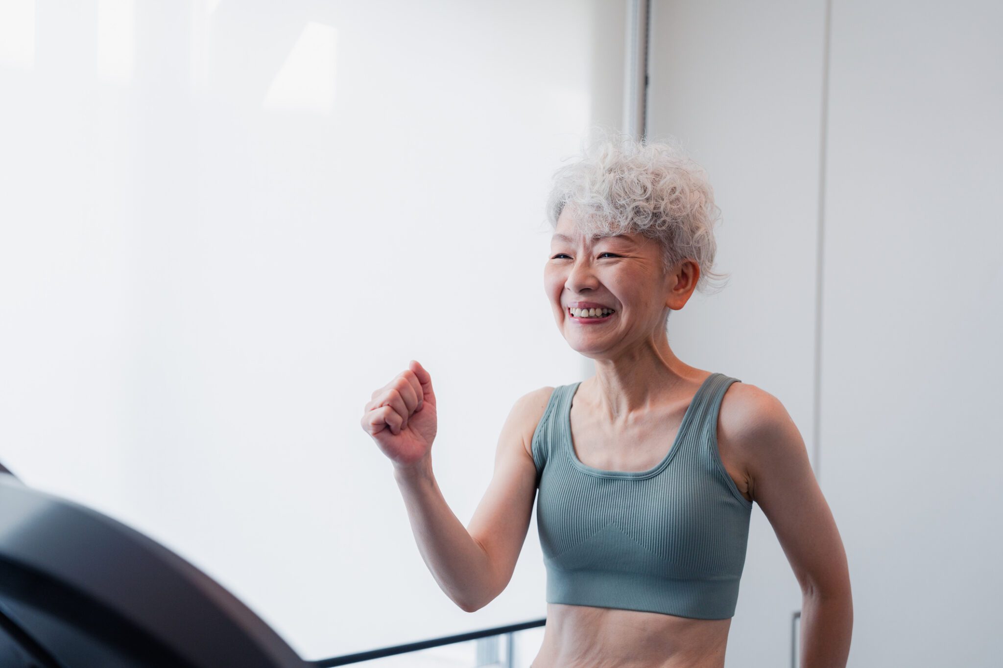 Senior Woman Riding A Running Machine At The Gym
